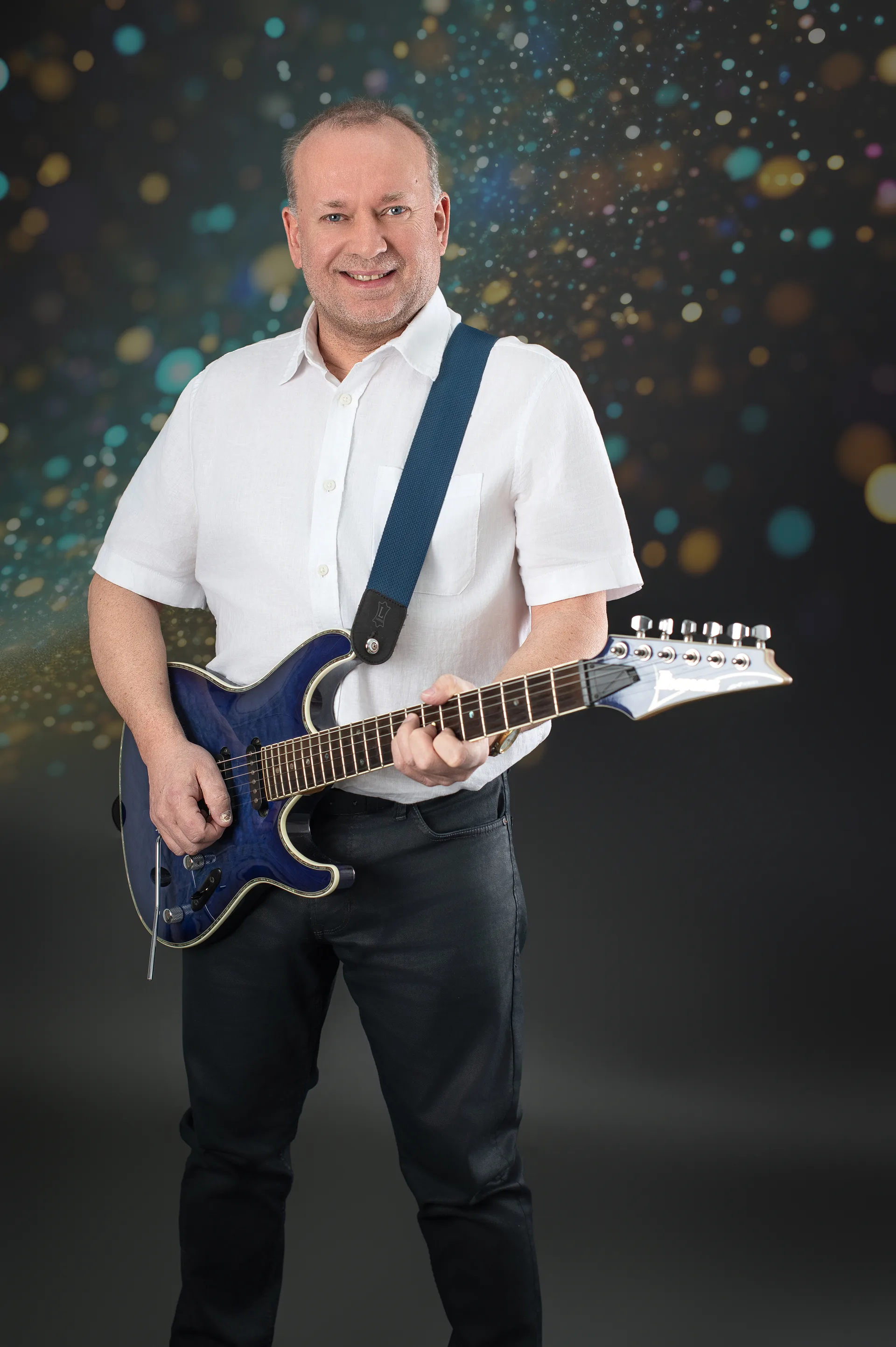 Gerald Stefan Allmann mit E-Gitarre vor Bokeh-Hintergrund