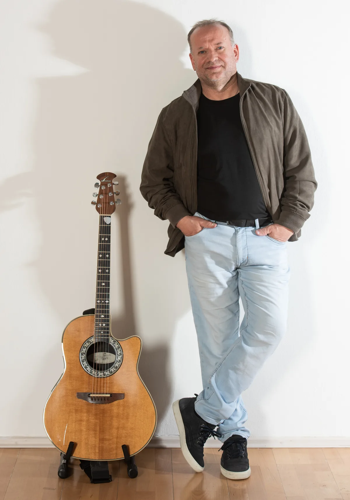 Gerald Stefan Allmann neben Akustikgitarre an der Wand