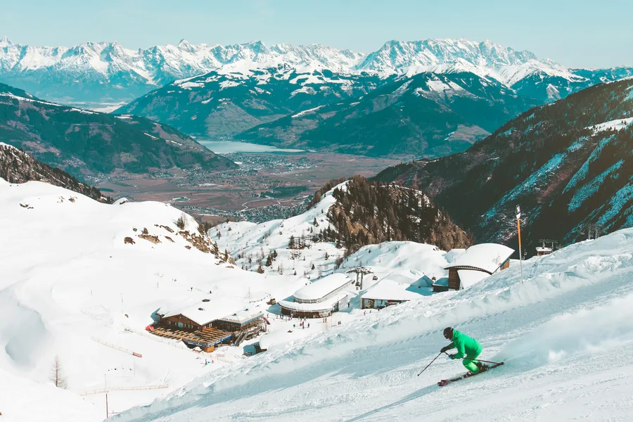 Verschneite Skilandschaft mit Hütten und Skifahrer auf der Piste